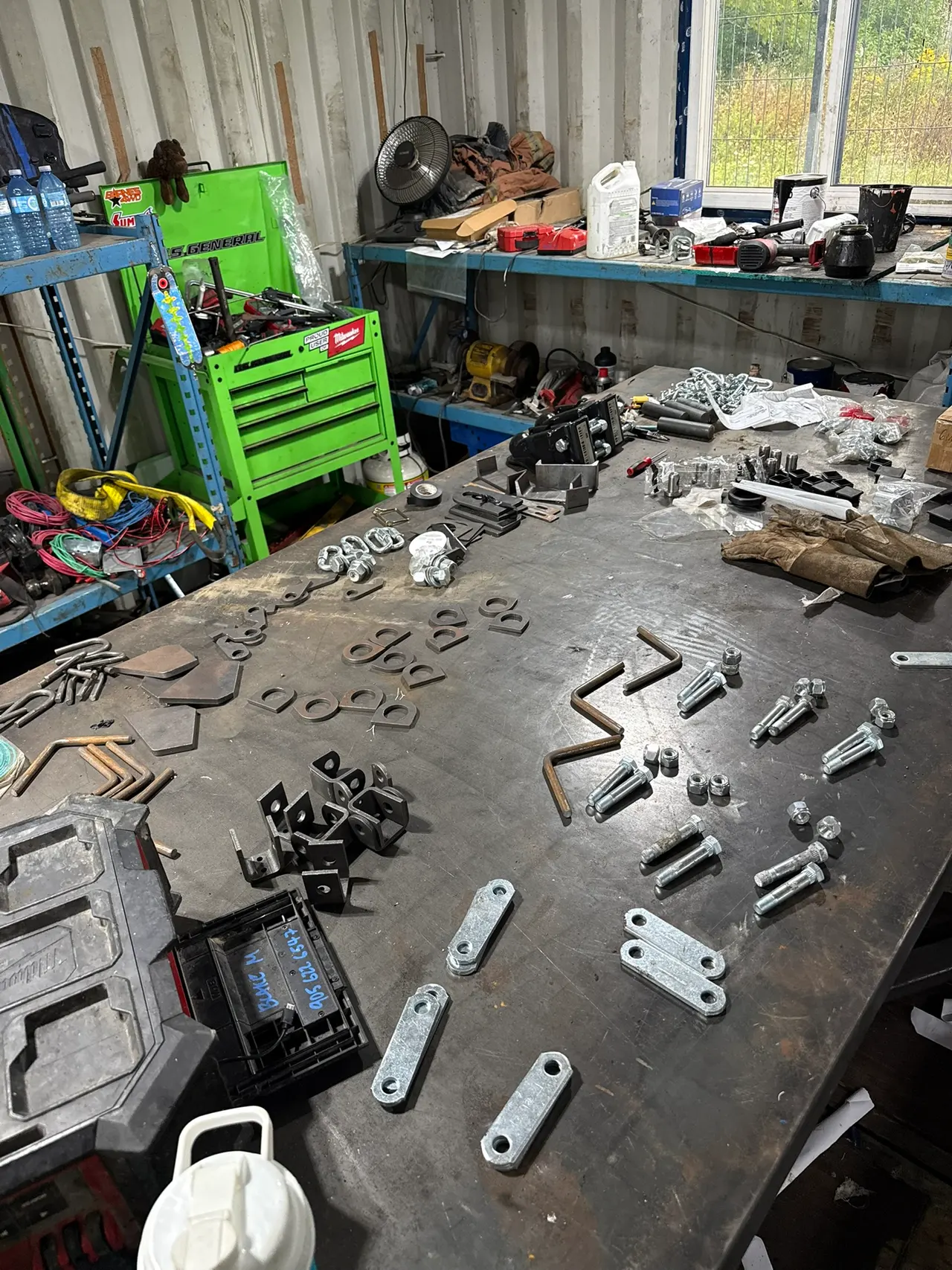 Custom metal brackets, small mounts and fittings laid out on the fabrication bench