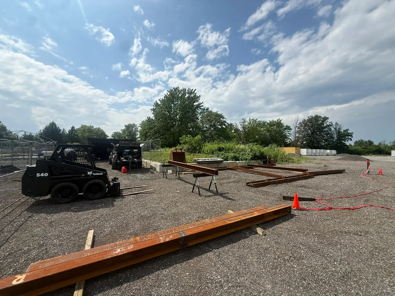 Steel beams laid out beside the mobile welding truck at an outdoor worksite